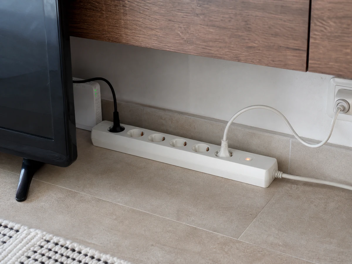 Regleta con protección contra sobretensiones detrás del mueble del televisor